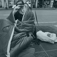 Homeless Korean war vet wrapped in red blanked, in need of help.